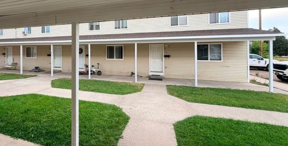 The covered front walkway of a Clover Creek Heights fourplex, with lawn and concrete paths out front